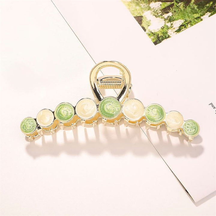 The SOHO Becca Hair Claw - Lime features a chic gold design with alternating green and cream circular stones, making it a stylish SOHO accessory for securing your hairstyle.