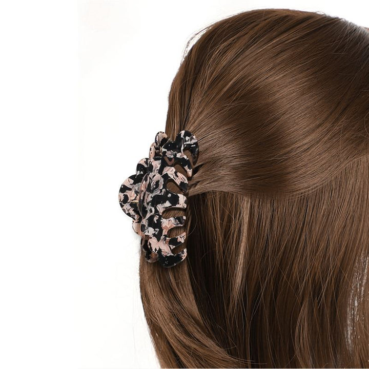 A close-up of long brown hair partially pulled back with the SOHO Callie Hair Claw - Blush, a large marble clip by SOHO featuring black, beige, and pink patterns.