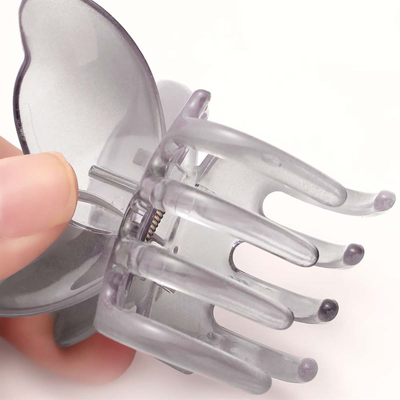 A close-up of a hand holding the SOHO Ella Hair Claw in Arctic by SOHO, showcasing its translucent gray design, sturdy spring mechanism, and wide curved prongs—ideal for creating cute hairstyles.