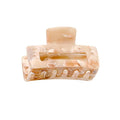 Die SOHO Leia Mini Hair Claw in Beige Marble verfügt über einen rechteckigen Ausschnitt und ineinandergreifende Zinken, die ein müheloses Styling ermöglichen. Diese hellbeige marmorierte Klammer wird vor einem weißen Hintergrund gezeigt.