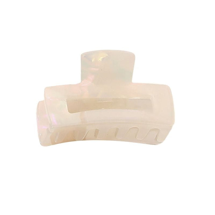 The SOHO Leia Mini Hair Claw - Pearl by SOHO features a cream-colored, iridescent finish, rectangular cutout, and curved teeth—ideal for securing your hairstyle.