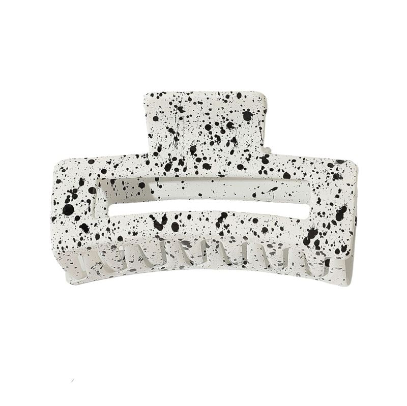 The SOHO Luva Hair Claw - White features a black splash pattern, wide teeth, and a top hinge for easy use. This secure SOHO clip adds a stylish touch to any look.