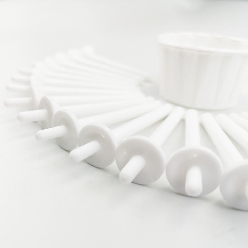 A close-up of several UNIQ Nose Wax Kit white applicator sticks with flat round ends, arranged semi-circularly with a small cup behind them, all on a white surface. Brand: UNIQ.