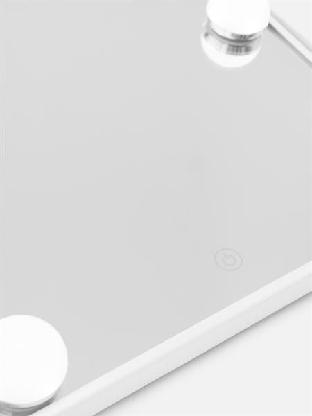 A close-up of the UNIQ XL Hollywood make-up mirror by UNIQ, white-framed with a touch function, showing two round silver magnets and a subtle power button symbol on the reflective surface.